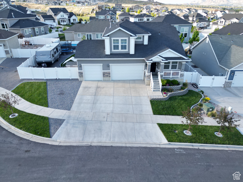 View of front of property featuring a gate, a residential view, driveway, an attached garage, and a shingled roof