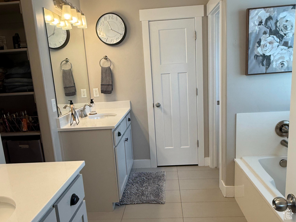 Full bathroom featuring a sink, tile patterned flooring, two vanities, a bath, and a closet