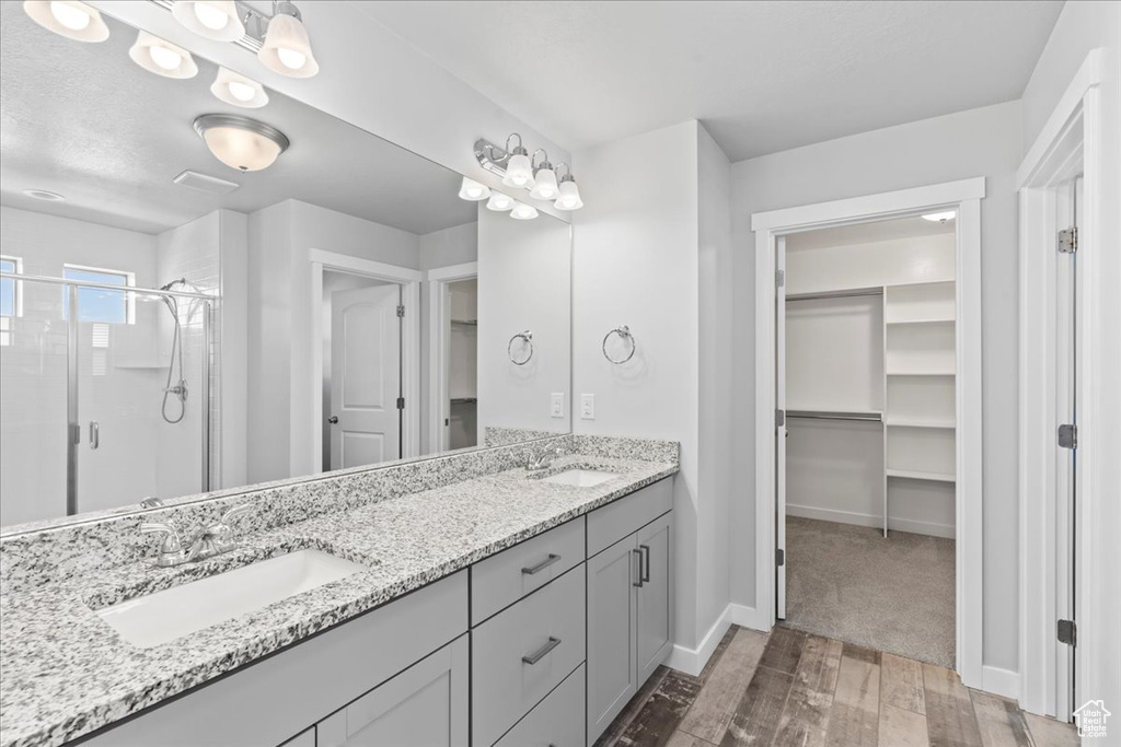 Full bathroom with a sink, double vanity, a stall shower, and hardwood / wood-style floors
