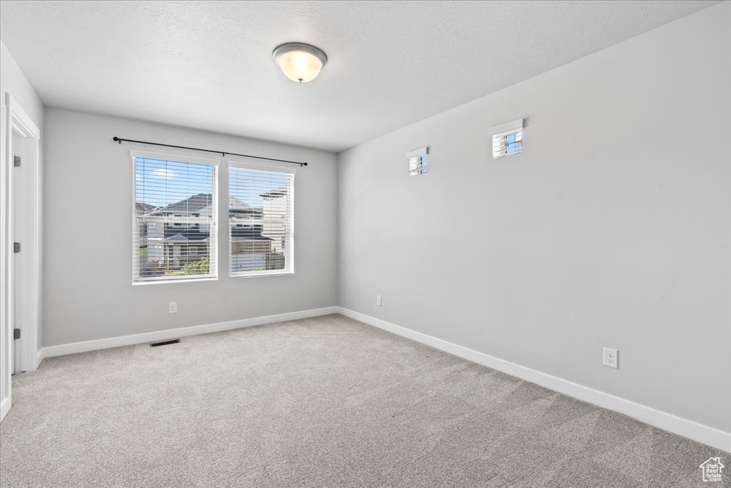Spare room with visible vents, carpet, and baseboards