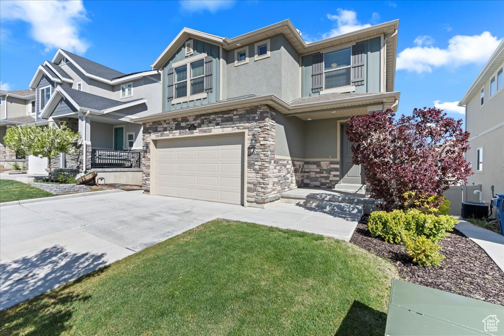 View of front of house with stone siding, a garage, stucco siding, concrete driveway, and covered porch