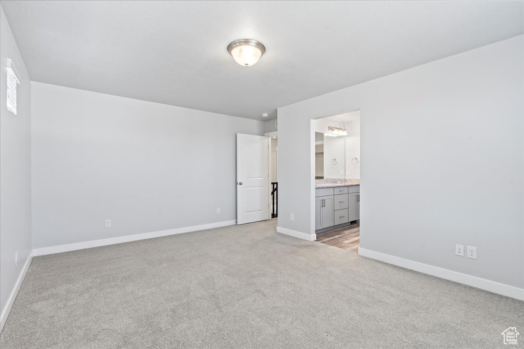 Unfurnished bedroom featuring light colored carpet, baseboards, and ensuite bathroom