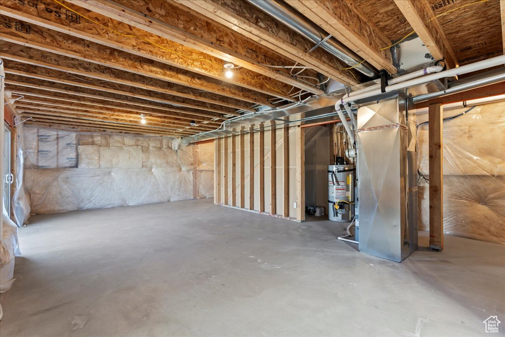 Unfinished below grade area featuring heating unit and gas water heater
