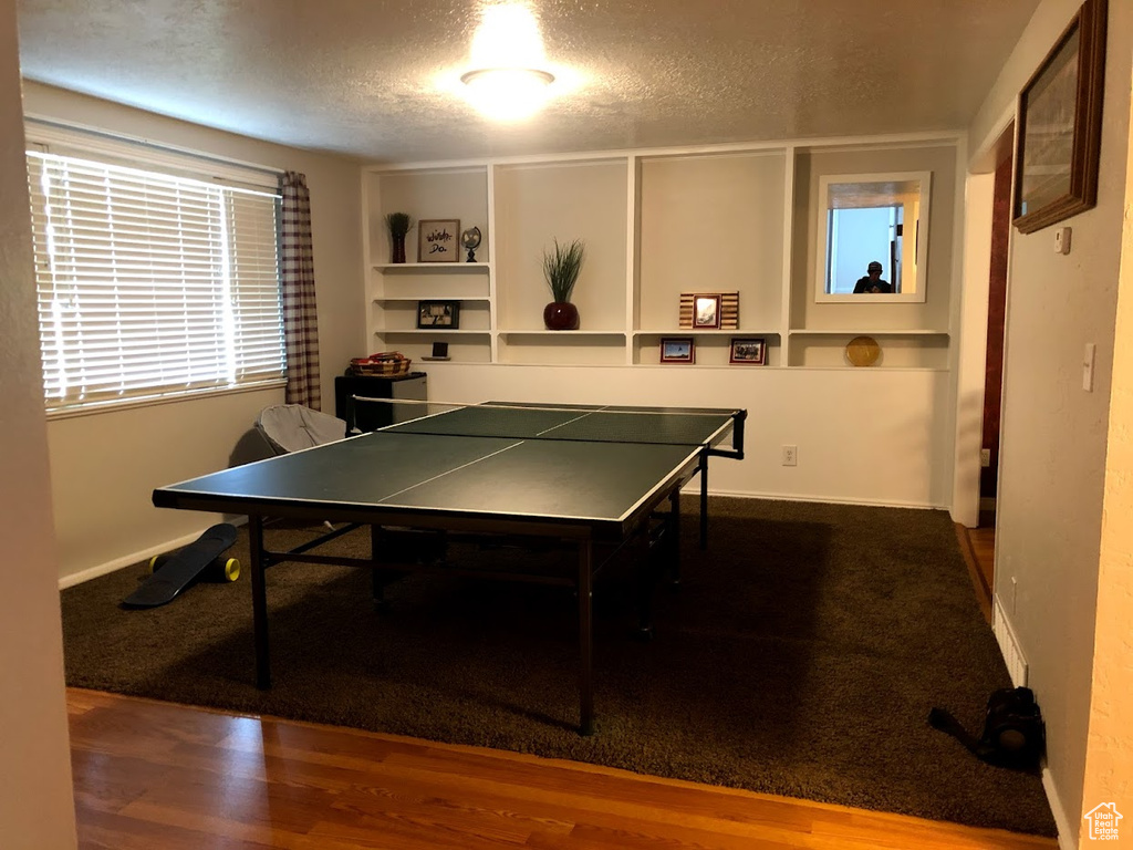Playroom with baseboards, a textured ceiling, and wood finished floors