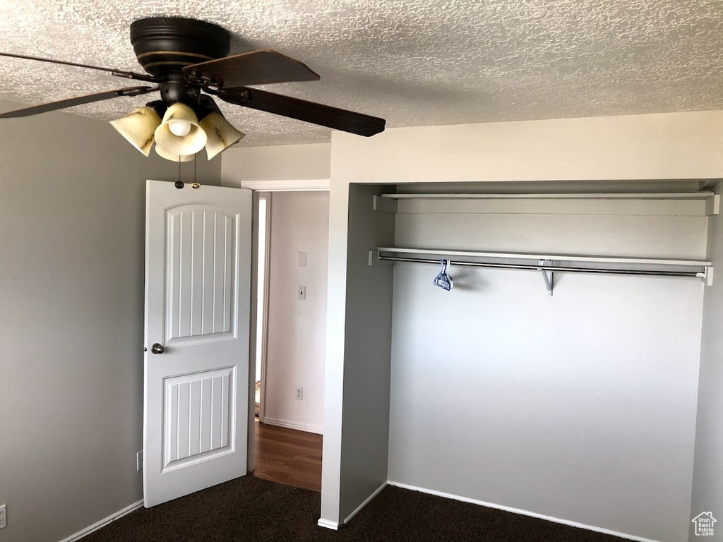 Unfurnished bedroom with baseboards, a ceiling fan, a textured ceiling, and dark carpet