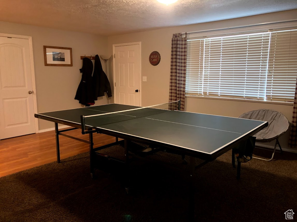 Game room featuring baseboards, a textured ceiling, and wood finished floors