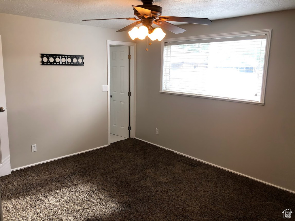 Carpeted spare room with baseboards, ceiling fan, and a textured ceiling