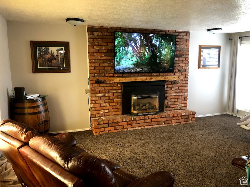Living room featuring carpet floors, a textured ceiling, a brick fireplace, and baseboards