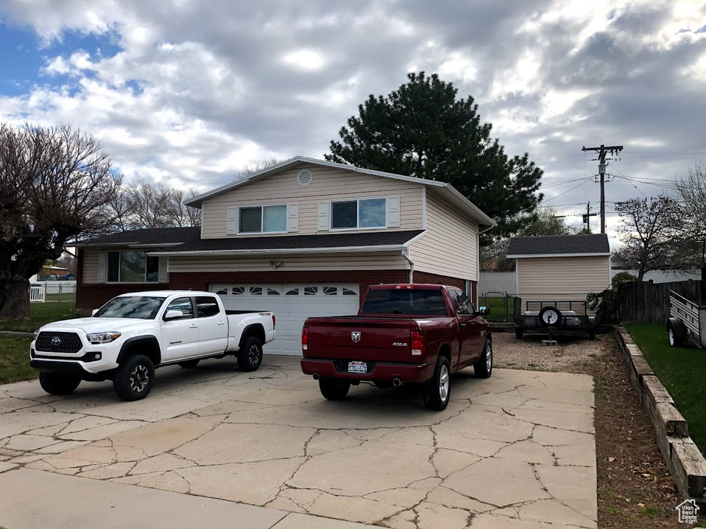 View of front facade featuring fence, an attached garage, and driveway