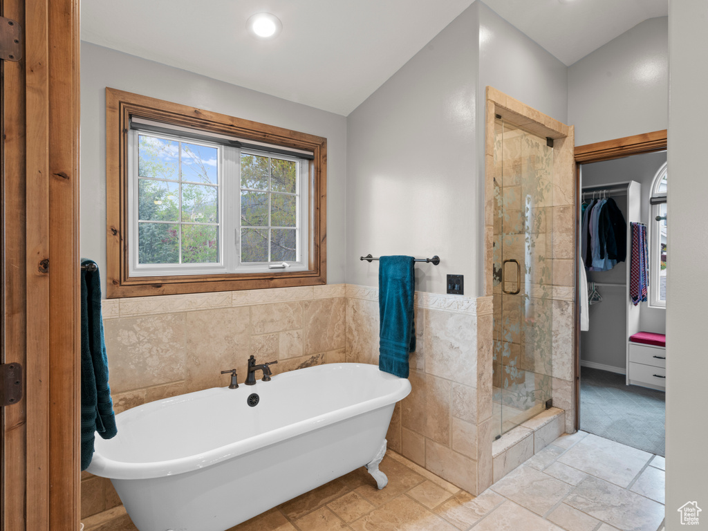 Bathroom with a wainscoted wall, recessed lighting, tile walls, a shower stall, and a soaking tub