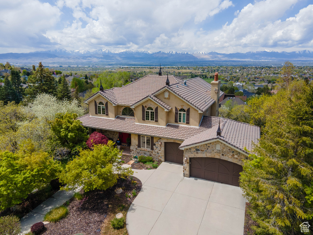 View of front of home featuring a mountain view, a tiled roof, concrete driveway, and stucco siding