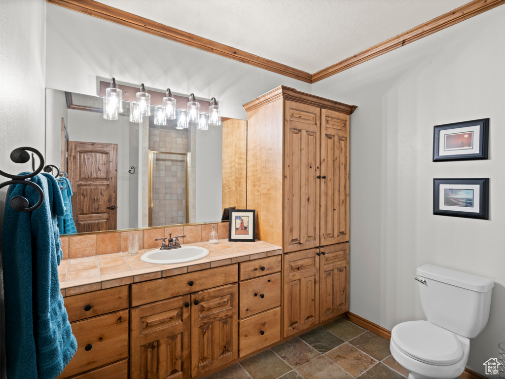 Full bath with a stall shower, baseboards, toilet, ornamental molding, and stone tile floors