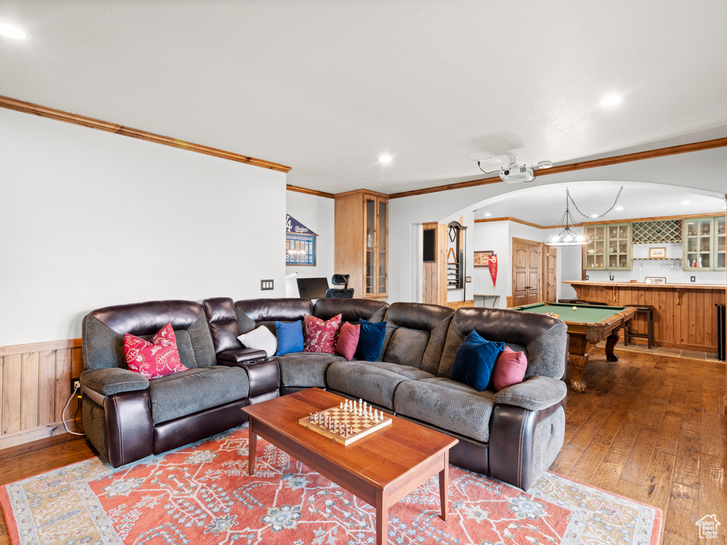 Living room with wood-type flooring, arched walkways, wainscoting, and ornamental molding