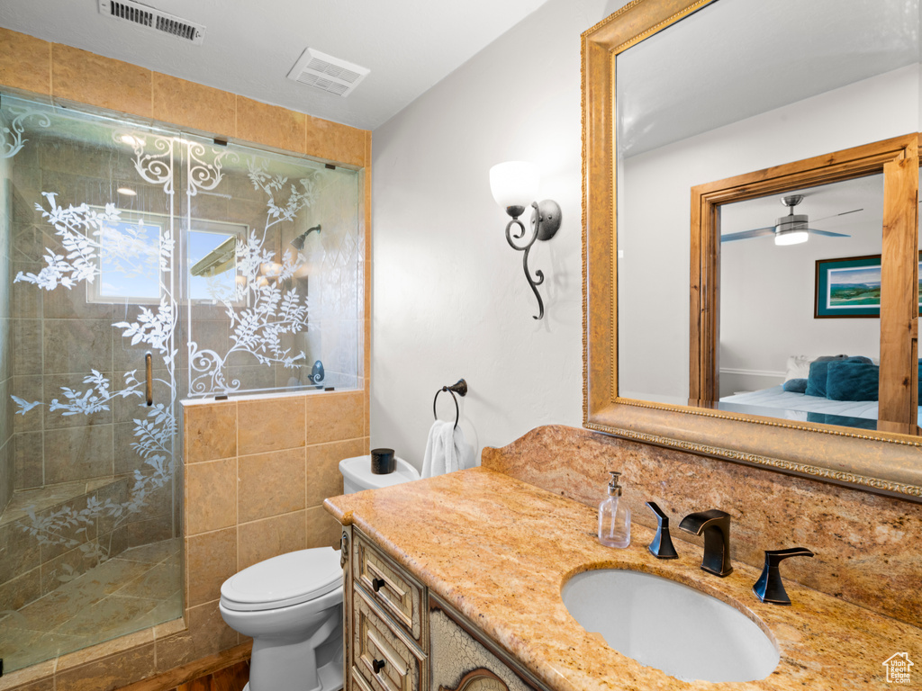 Bathroom featuring visible vents, vanity, toilet, tiled shower, and connected bathroom