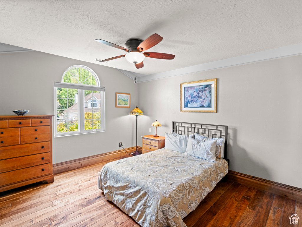Bedroom featuring a textured ceiling, ceiling fan, baseboards, and hardwood / wood-style flooring