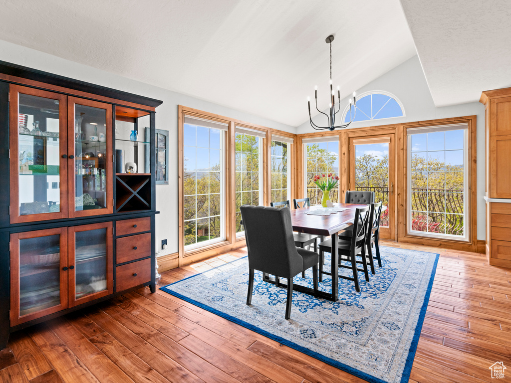 Dining room with lofted ceiling, hardwood / wood-style flooring, and a chandelier