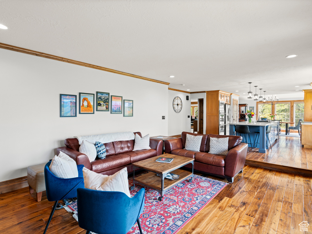 Living room with crown molding, recessed lighting, baseboards, and light wood-type flooring