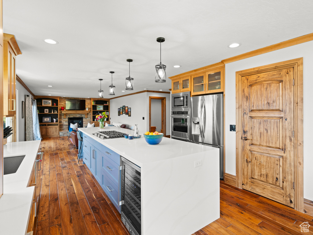 Kitchen featuring appliances with stainless steel finishes, beverage cooler, dark wood finished floors, recessed lighting, and glass insert cabinets