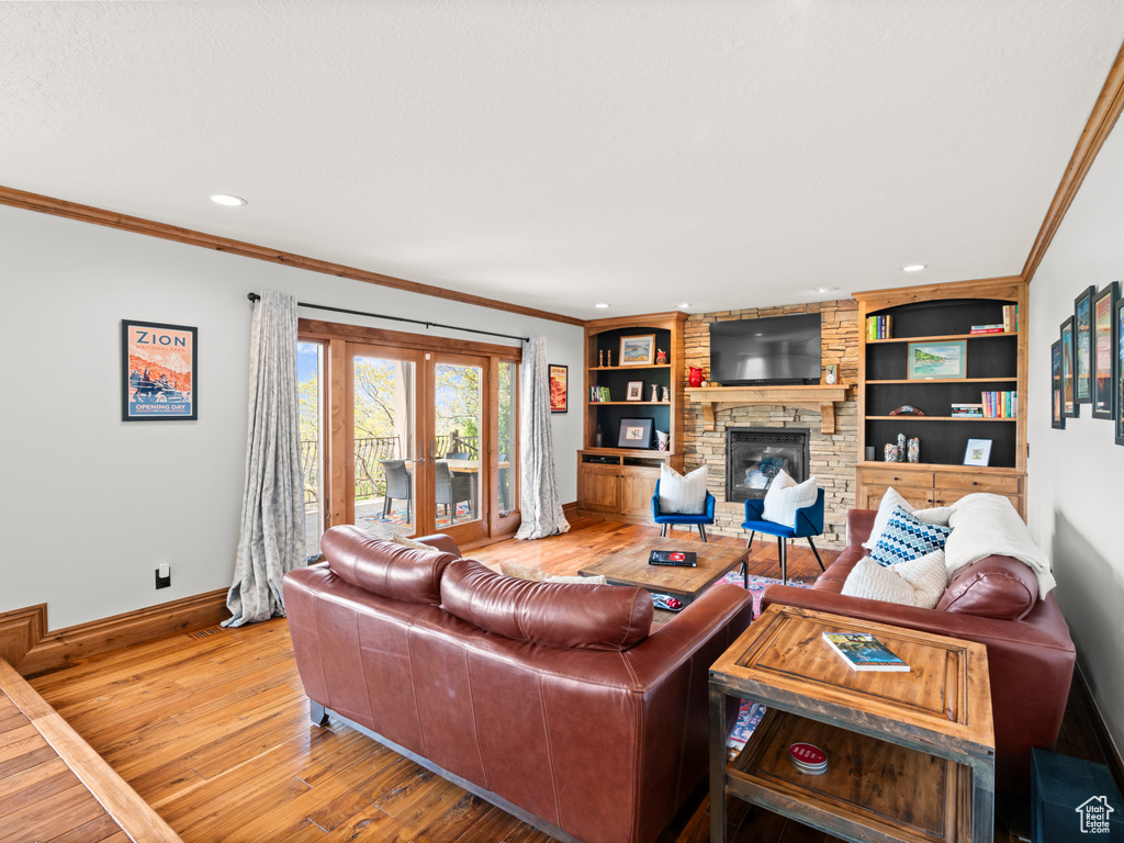 Living area with crown molding, a fireplace, french doors, baseboards, and hardwood / wood-style flooring