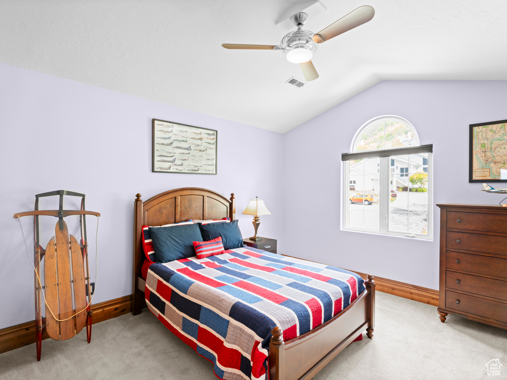 Bedroom with visible vents, baseboards, lofted ceiling, and light carpet