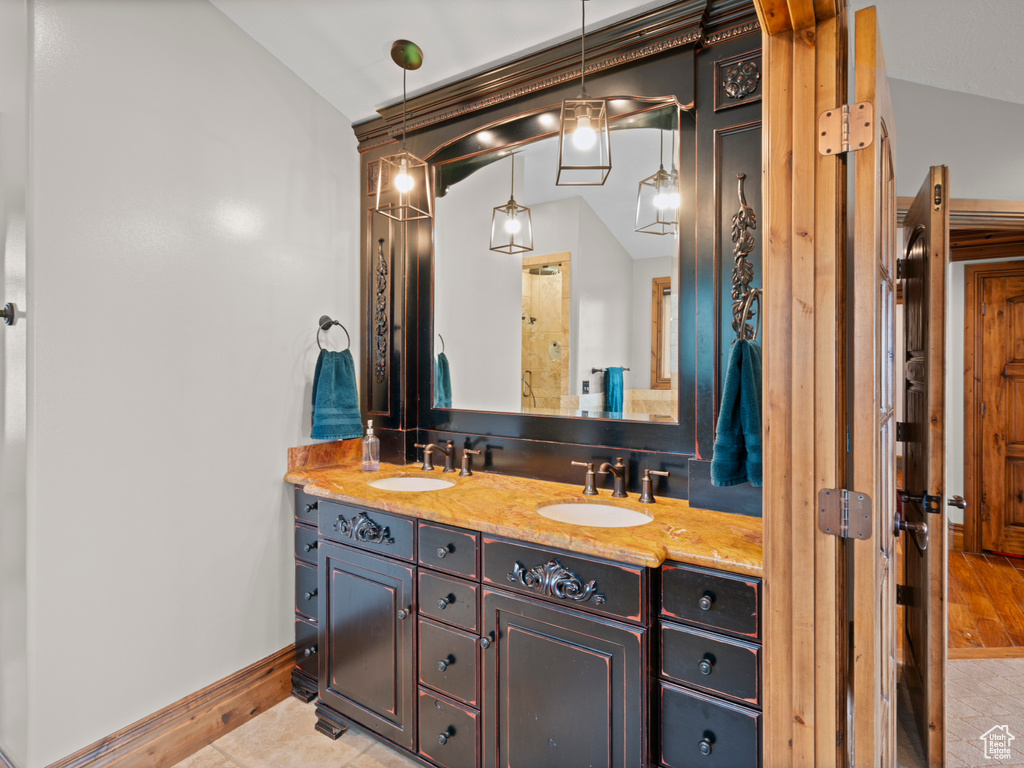 Full bathroom with double vanity, a sink, baseboards, and vaulted ceiling