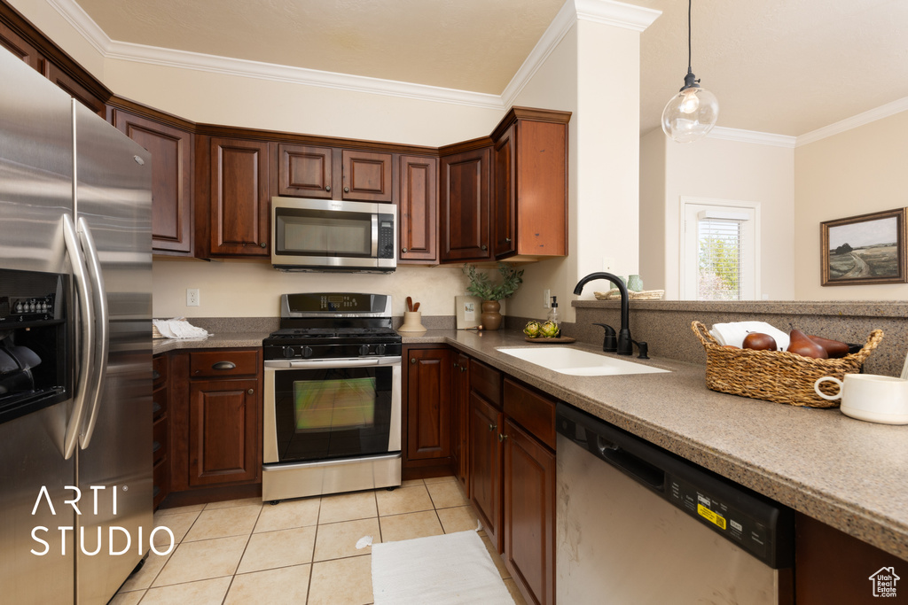 Kitchen with decorative light fixtures, crown molding, a sink, light tile patterned floors, and stainless steel appliances