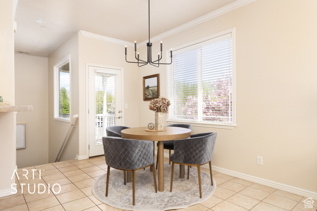 Dining area featuring crown molding, light tile patterned flooring, baseboards, and a notable chandelier