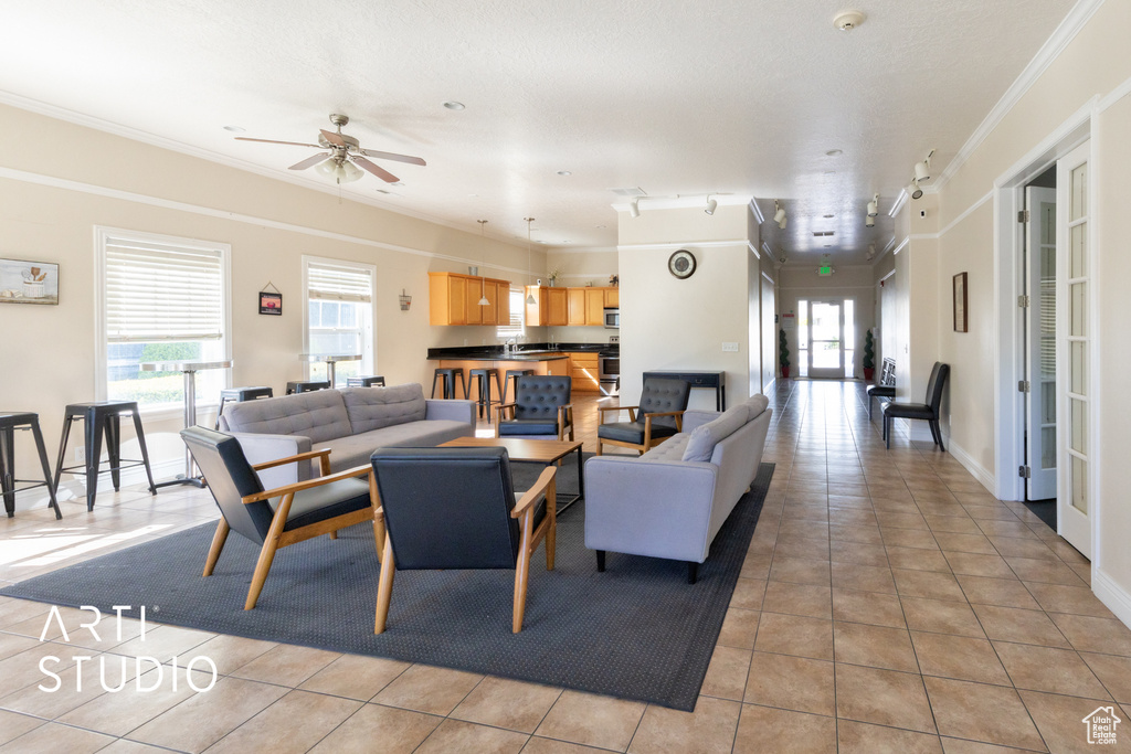 Living area with crown molding, ceiling fan, and light tile patterned floors