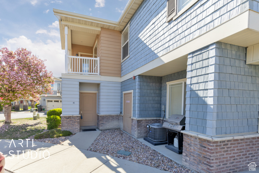 Property entrance featuring brick siding, cooling unit, and a balcony
