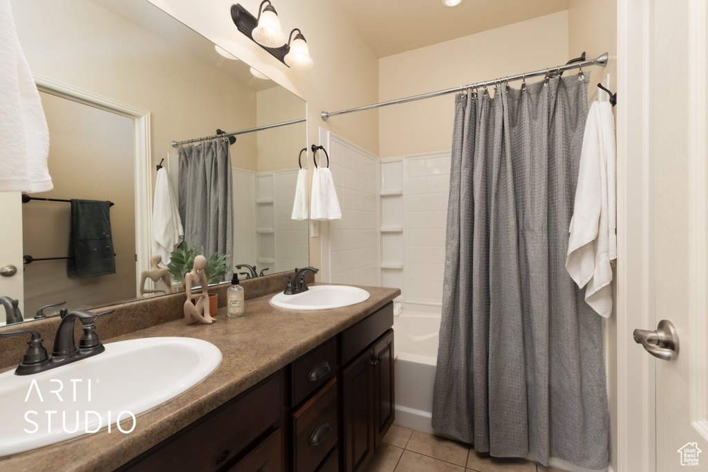 Full bathroom featuring double vanity, tile patterned floors, a sink, and shower / bath combo