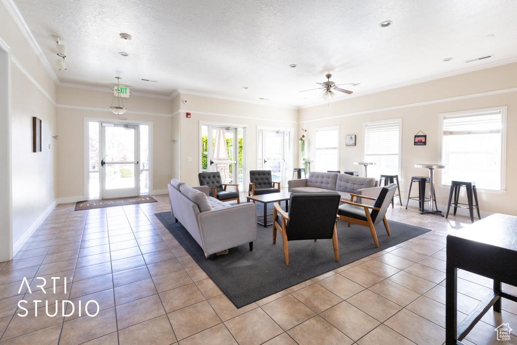 Living room with crown molding, a ceiling fan, baseboards, light tile patterned floors, and visible vents