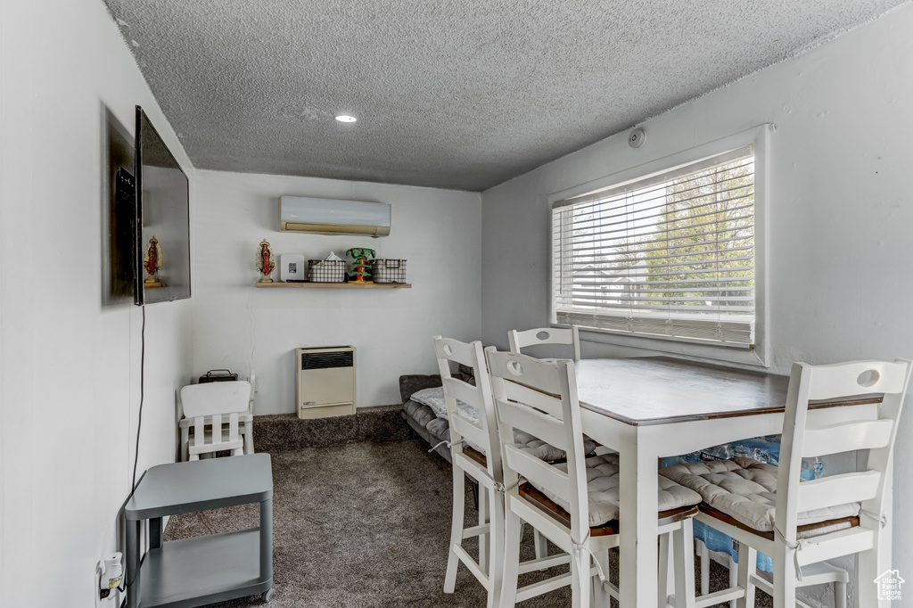 Dining area with heating unit, a wall unit AC, carpet, and a textured ceiling