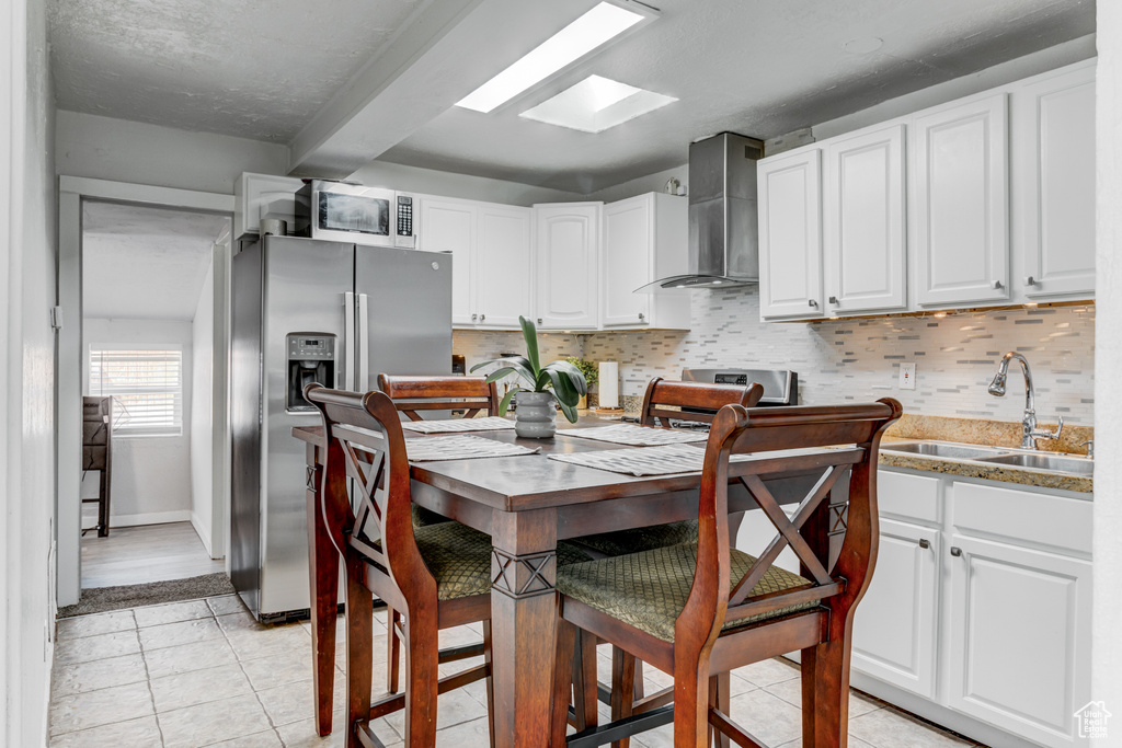 Kitchen featuring a sink, wall chimney exhaust hood, tasteful backsplash, and stainless steel appliances