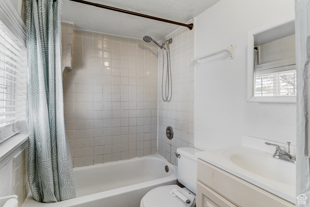 Bathroom with vanity, toilet, a textured ceiling, and shower / tub combo with curtain