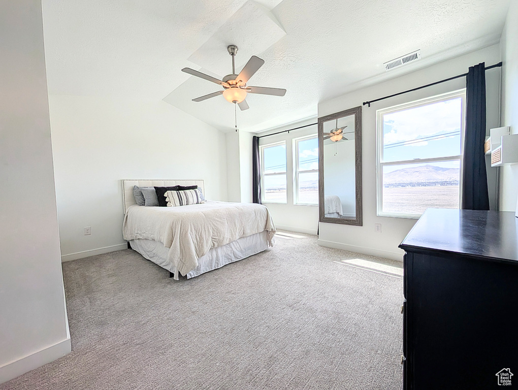 Carpeted bedroom featuring ceiling fan, a textured ceiling, visible vents, baseboards, and lofted ceiling