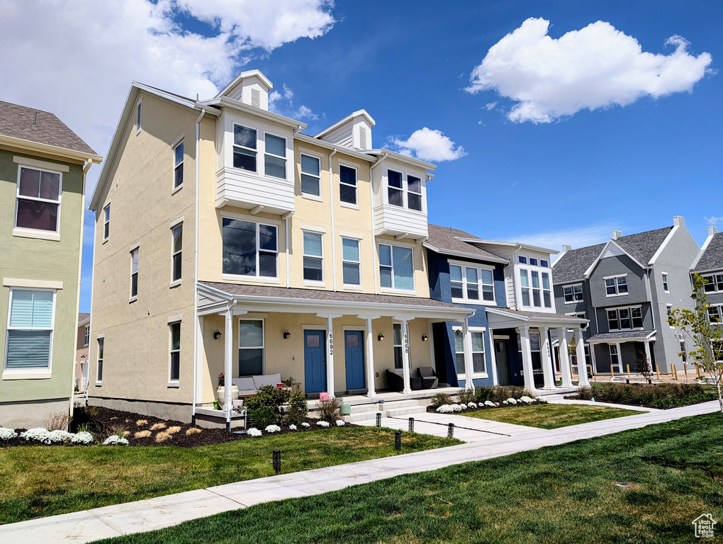 View of property featuring stucco siding, a porch, and a front lawn