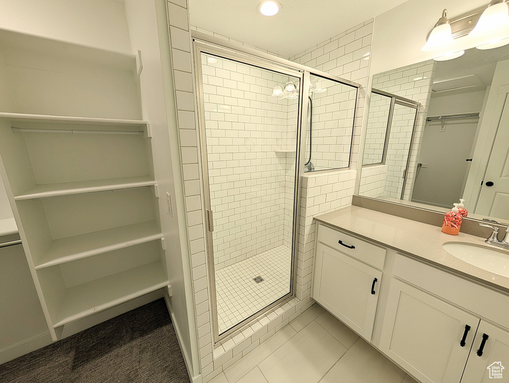 Full bath featuring vanity, tile patterned floors, a walk in closet, and a stall shower