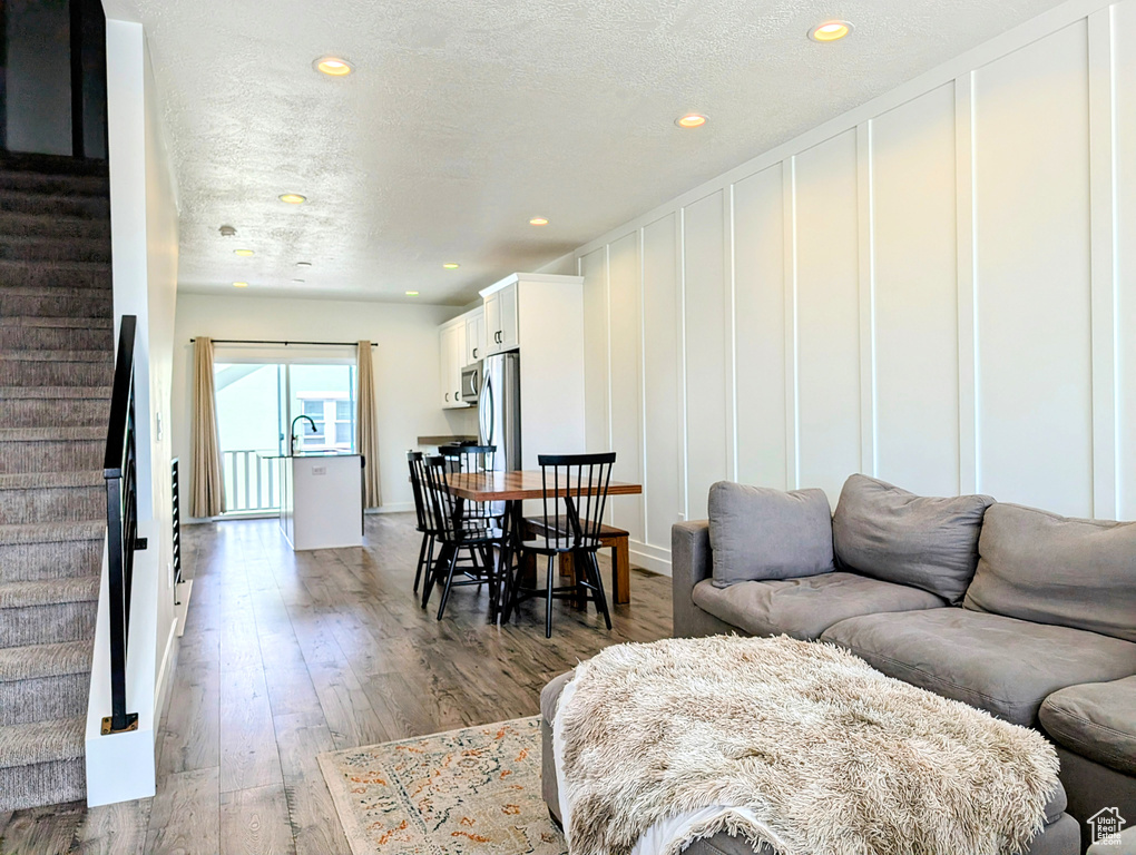 Living area with stairway, a textured ceiling, recessed lighting, and wood finished floors