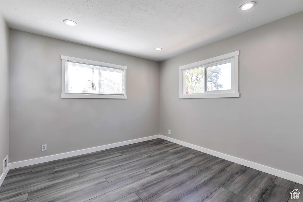 Unfurnished room featuring recessed lighting, baseboards, dark wood-style flooring, and visible vents
