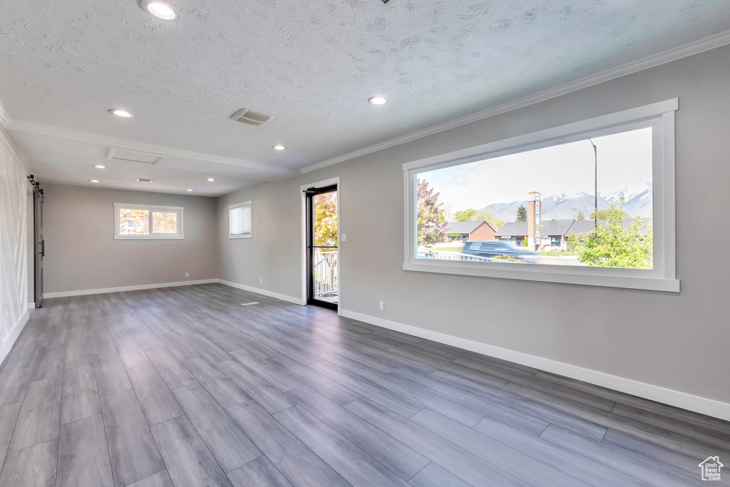 Spare room with ornamental molding, wood finished floors, baseboards, recessed lighting, and a textured ceiling