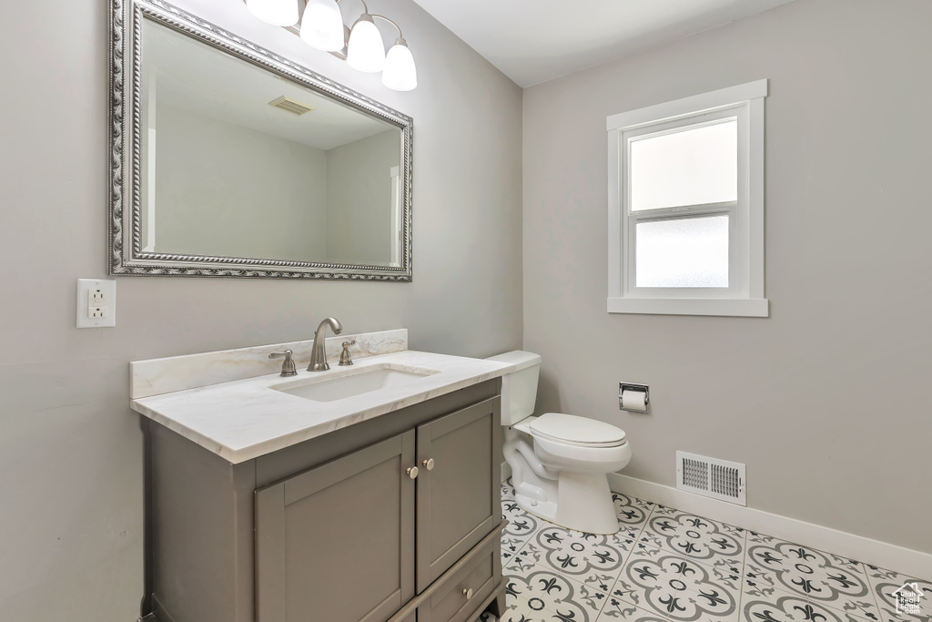Half bath with visible vents, baseboards, toilet, and vanity