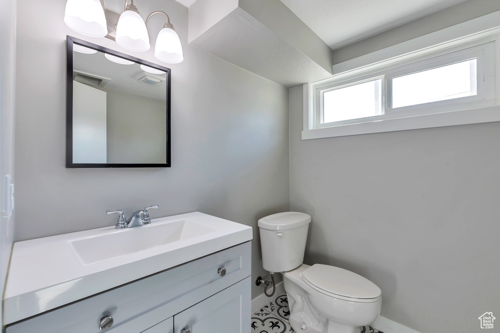 Bathroom with baseboards, tile patterned flooring, toilet, and vanity