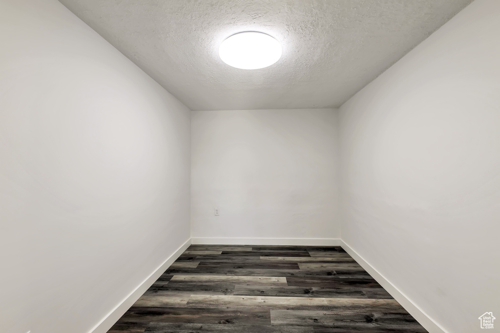 Unfurnished room with baseboards, a textured ceiling, and dark wood-style floors