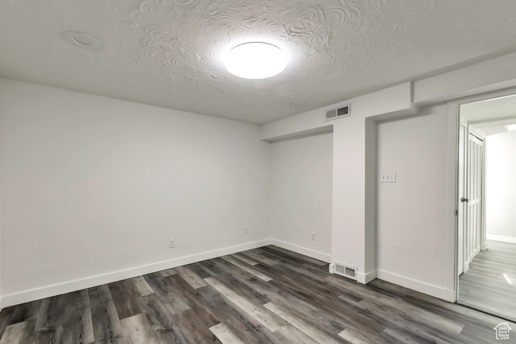 Empty room featuring visible vents, baseboards, and dark wood-style floors