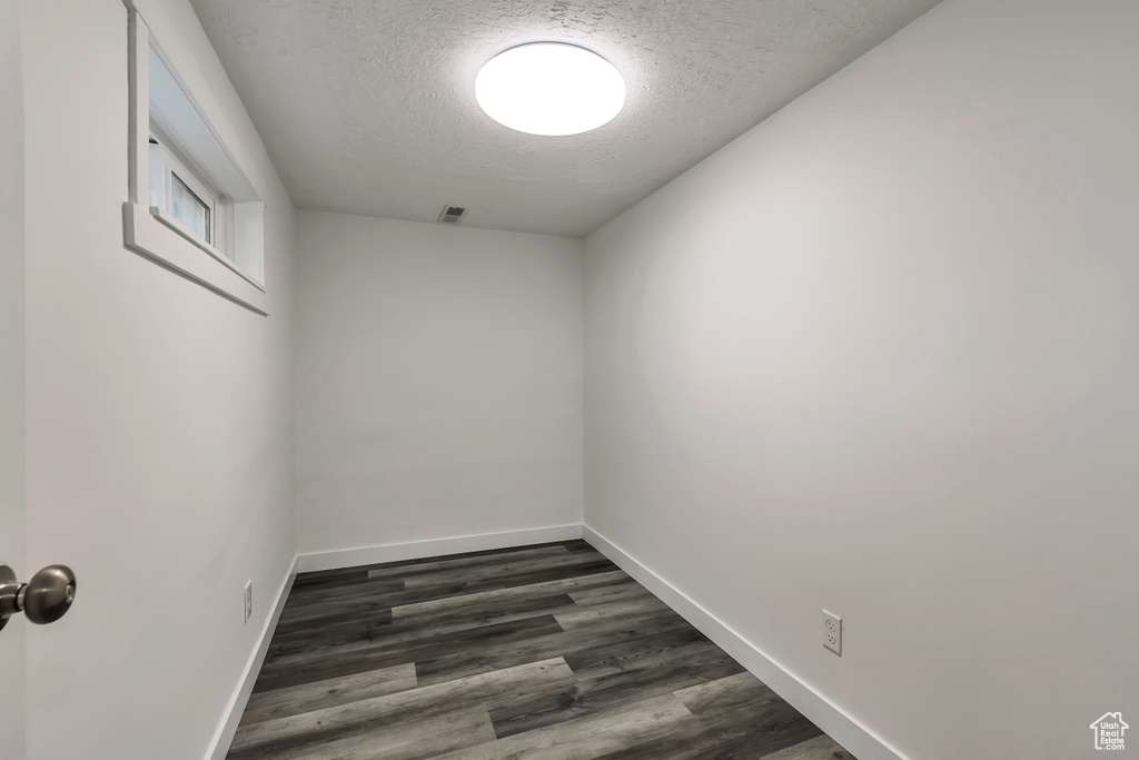 Unfurnished room with baseboards, a textured ceiling, dark wood-style flooring, and visible vents