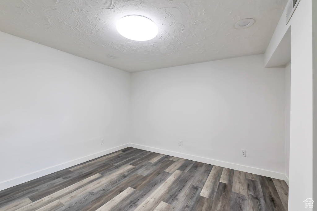 Spare room featuring baseboards, dark wood-style flooring, a textured ceiling, and visible vents