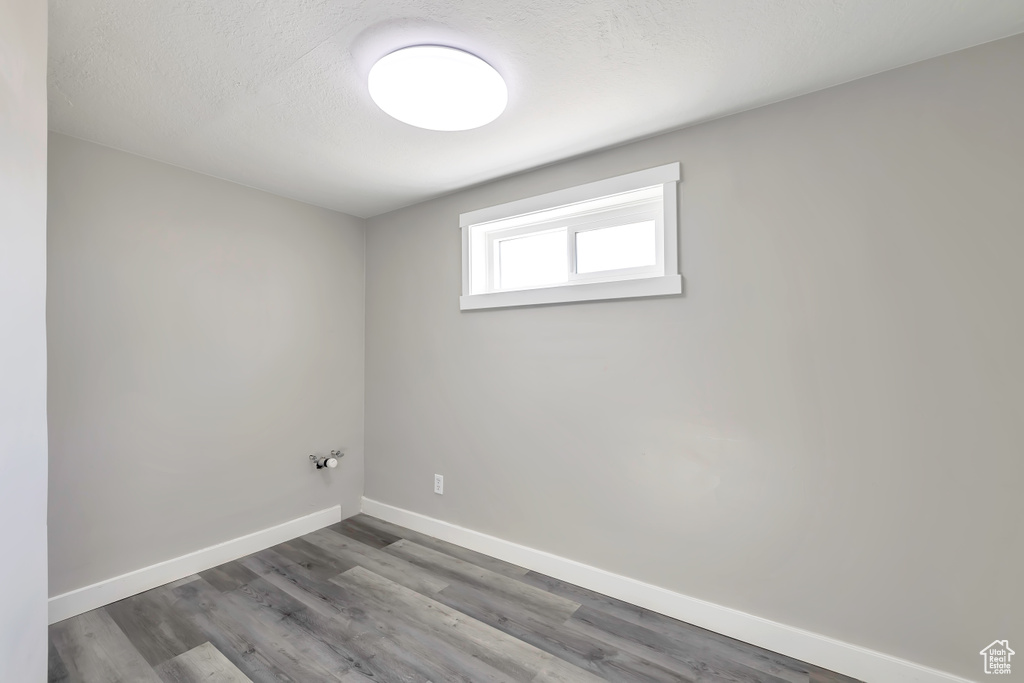 Interior space with a textured ceiling, baseboards, and wood finished floors