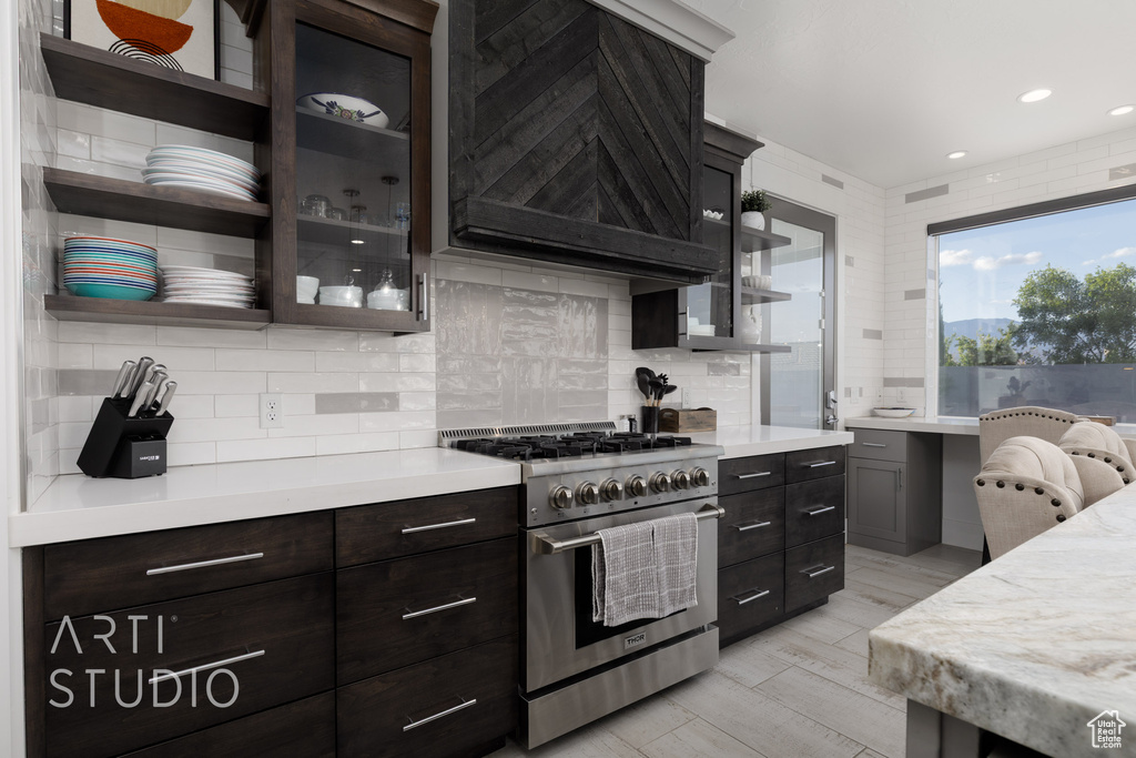 Kitchen featuring light countertops, glass insert cabinets, tasteful backsplash, and high end stainless steel range oven