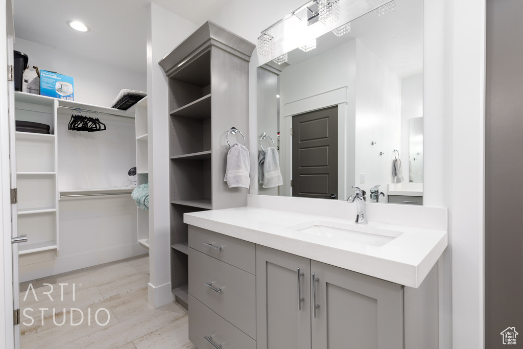 Bathroom with vanity, a walk in closet, and wood finished floors