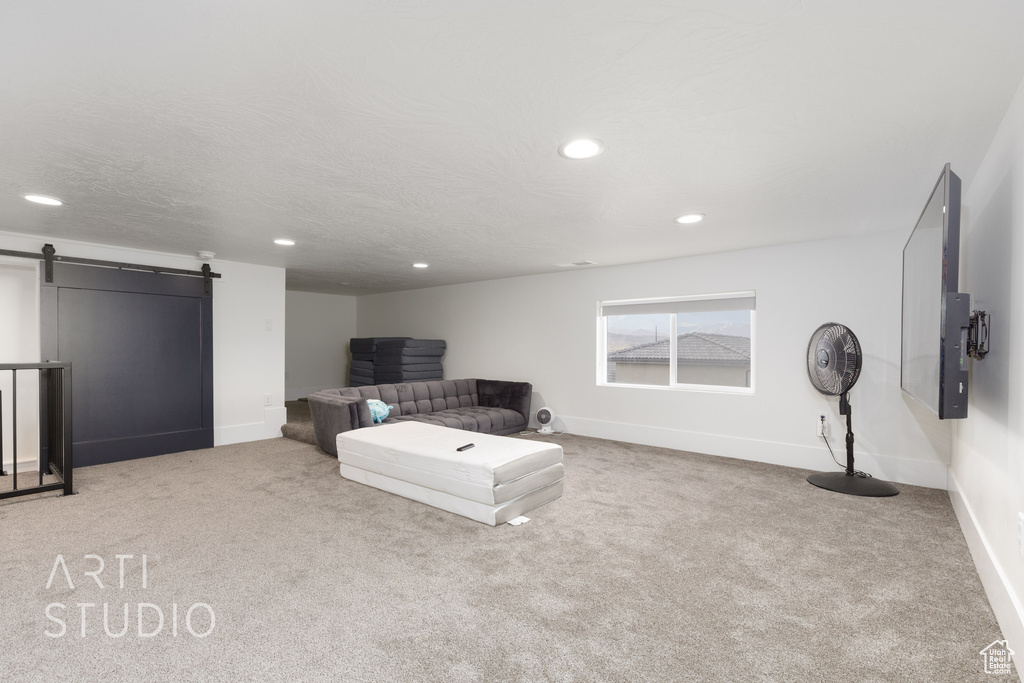 Living room with carpet flooring, recessed lighting, and a barn door
